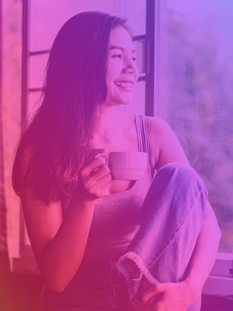 Image of a woman looking out the window and drinking tea